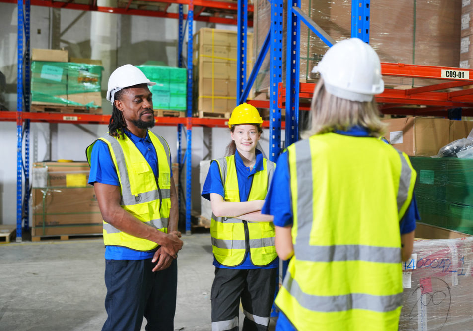 Worker working in large warehouse holding paper chart check list checking the material compare with the boxes wrapped with plastic keep on wooden pallet ready to ship to customer